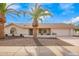 Charming single-story home featuring a two-car garage, desert landscaping, and beautiful palm trees at 13747 W Tartan Dr, Sun City West, AZ 85375