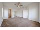 Large primary bedroom featuring neutral carpeting, a ceiling fan, and connecting doors to a bathroom and hallway at 15222 N 138Th Dr, Surprise, AZ 85379