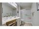 Bright bathroom featuring a vanity with white cabinets, a shower with sliding glass doors, and wood-style flooring at 16118 W Vista North Dr, Sun City West, AZ 85375