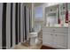 Well-lit bathroom featuring white cabinets, toilet, and a striking black and white striped shower curtain at 16118 W Vista North Dr, Sun City West, AZ 85375