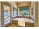 Bathroom soaking tub next to a large window with a backyard view and a door leading to the outside at 16402 N 48Th Way, Scottsdale, AZ 85254