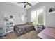 Well-lit bedroom featuring a ceiling fan, a large window with plantation shutters, and cute decor at 16813 W Hammond St, Goodyear, AZ 85338