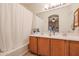 Bathroom featuring a double sink vanity with wood cabinets, tub shower with curtain and large mirrors at 1722 N 77Th Gln, Phoenix, AZ 85035