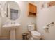 This bathroom features a pedestal sink, wood cabinet, and standard toilet at 1722 N 77Th Gln, Phoenix, AZ 85035