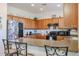 Eat-in kitchen with oak cabinets, tile floors, breakfast bar, and black appliances at 1722 N 77Th Gln, Phoenix, AZ 85035