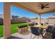 Covered patio with an outdoor dining set, ceiling fan and a beautifully landscaped backyard at 1777 E Dubois Ave, Gilbert, AZ 85298