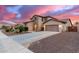 Charming two-story home featuring stone accents, desert landscaping, and a spacious two car driveway at sunset at 19349 W Oregon Ave, Litchfield Park, AZ 85340