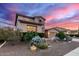 Charming two-story home featuring stone accents, desert landscaping, and a spacious two car driveway at sunset at 19349 W Oregon Ave, Litchfield Park, AZ 85340