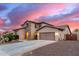 Charming two-story home featuring stone accents, desert landscaping, and a spacious two car driveway at sunset at 19349 W Oregon Ave, Litchfield Park, AZ 85340