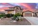 Charming two-story home featuring stone accents, desert landscaping, and a spacious two car driveway at sunset at 19349 W Oregon Ave, Litchfield Park, AZ 85340