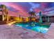 Twilight view of luxurious backyard pool with inviting lounge areas and lush tropical landscaping at 19349 W Oregon Ave, Litchfield Park, AZ 85340