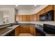 Kitchen with wood cabinetry, granite countertops, and black appliances at 19550 N Grayhawk Dr # 2038, Scottsdale, AZ 85255