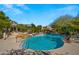 Community pool area with waterfall feature, trees, and comfortable lounge chairs for residents to enjoy at 19550 N Grayhawk Dr # 2038, Scottsdale, AZ 85255