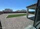 View of a gravel back yard with artificial turf, a covered patio, and surrounding neighborhood homes at 19889 W Annika Dr, Litchfield Park, AZ 85340