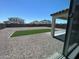 View of a gravel back yard with artificial turf, a covered patio, and surrounding neighborhood homes at 19889 W Annika Dr, Litchfield Park, AZ 85340