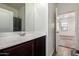 A bathroom boasting a vanity with dark wood cabinetry and a decorative mirror, reflecting natural light at 20183 W Monroe St, Buckeye, AZ 85326