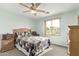 Cozy bedroom with light blue walls, ceiling fan, and view of the neighborhood through a bright window at 21520 W Watkins St, Buckeye, AZ 85326