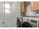 Well-lit laundry room with modern washer and dryer, wood cabinets, and a view from the window at 21520 W Watkins St, Buckeye, AZ 85326