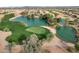 Stunning aerial view of the community with lush green golf course, serene lakes and mountain views in the distance at 21798 N Ingram Ct, Maricopa, AZ 85138