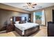 Cozy main bedroom featuring a king-size bed, dark brown accent wall, ceiling fan, and window with natural light at 21798 N Ingram Ct, Maricopa, AZ 85138