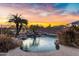 Beautiful pool area with rock waterfall, landscaping and a colorful sunset sky at 21798 N Ingram Ct, Maricopa, AZ 85138