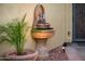 Unique outdoor fountain with intricate details, surrounded by lush potted plants and greenery at 23236 N Caleta Ct, Sun City West, AZ 85375