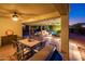 Covered patio area with a dining table, pool views, and outdoor lighting for evening relaxation and entertainment at 23236 N Caleta Ct, Sun City West, AZ 85375