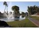 Scenic view of community pond with a fountain, walking path, and mature trees at 26405 S Lakewood Dr, Sun Lakes, AZ 85248