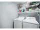 Functional laundry room with white washer and dryer and convenient shelving for storage at 30480 N 128Th Ln, Peoria, AZ 85383