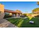 Inviting backyard featuring an artificial grass lawn, a covered patio, outdoor seating, and mature landscaping at 315 W Sonoma Dr, Litchfield Park, AZ 85340