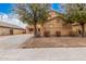 Charming two-story home featuring a three-car garage, mature trees, and a well-maintained, light-colored exterior at 38274 N Tumbleweed Ln, San Tan Valley, AZ 85140