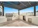 This outdoor kitchen has a built-in stainless steel grill and counter space under a modern pergola at 3964 E Penedes Dr, Gilbert, AZ 85298