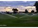 Sprinklers watering lush green golf course in an outdoor area with trees under an evening sky at 425 S Parkcrest -- # 323, Mesa, AZ 85206