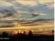 Wide exterior shot of a brilliant yellow, orange, and blue sunset over silhouettes of trees and distant mountains at 425 S Parkcrest -- # 323, Mesa, AZ 85206