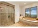 Luxurious primary bathroom features a walk-in shower, soaking tub, and views of the surrounding desert landscape at 42613 N 111Th Pl, Scottsdale, AZ 85262