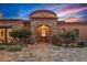 Close-up of the home's grand entrance, featuring custom stonework, a decorative door, and mature desert landscaping at 42613 N 111Th Pl, Scottsdale, AZ 85262