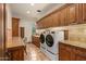 Spacious laundry room featuring granite counters, custom cabinets, and modern appliances at 42613 N 111Th Pl, Scottsdale, AZ 85262