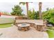 Inviting backyard featuring a stone fire pit with seating, lush greenery, and mature palm trees at 4365 E Anderson Dr, Phoenix, AZ 85032