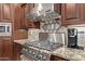 Close up of cooktop with stainless steel hood, granite countertops, and decorative backsplash at 4503 E Elmwood St, Mesa, AZ 85205