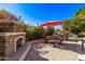 Outdoor patio featuring a stone fireplace, dining table and chairs, umbrella and mature landscaping at 4503 E Elmwood St, Mesa, AZ 85205