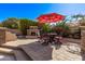 Outdoor seating area with umbrella, table, fireplace and chairs, surrounded by lush landscaping at 4503 E Elmwood St, Mesa, AZ 85205