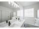 Bright bathroom featuring double sinks, sleek fixtures, glass block window, soaking tub, and a glass-enclosed shower at 4514 W Ellis St, Laveen, AZ 85339