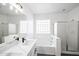 Bright bathroom featuring double sinks, sleek fixtures, glass block window, soaking tub, and a glass-enclosed shower at 4514 W Ellis St, Laveen, AZ 85339