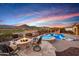 Luxurious backyard featuring a pool, spa, fire pit and outdoor kitchen under a beautiful Arizona sunset at 4820 N 210Th Ave, Buckeye, AZ 85396