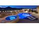 Beautifully lit resort-style backyard with a pool, hot tub, outdoor kitchen and desert landscaping at 4820 N 210Th Ave, Buckeye, AZ 85396