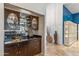 A sophisticated bar area with wood cabinetry, mirrored backsplash, and glass shelving at 6801 N 1St Pl, Phoenix, AZ 85012