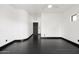 A minimalist room with hardwood floors and white walls featuring a dark door at 7601 E Roosevelt St # 1007, Scottsdale, AZ 85257