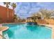 Community pool features a fountain and several palm trees, blue tiled trim and tan pergola at 7601 E Roosevelt St # 1007, Scottsdale, AZ 85257