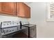 Practical laundry room featuring modern washer and dryer units with wooden cabinetry at 958 S Henry Ln, Gilbert, AZ 85296