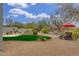 Beautiful backyard boasts lush greenery, a rock water feature, desert landscaping, and lounge chairs with red umbrella at 9781 E Gamble Ln, Scottsdale, AZ 85262